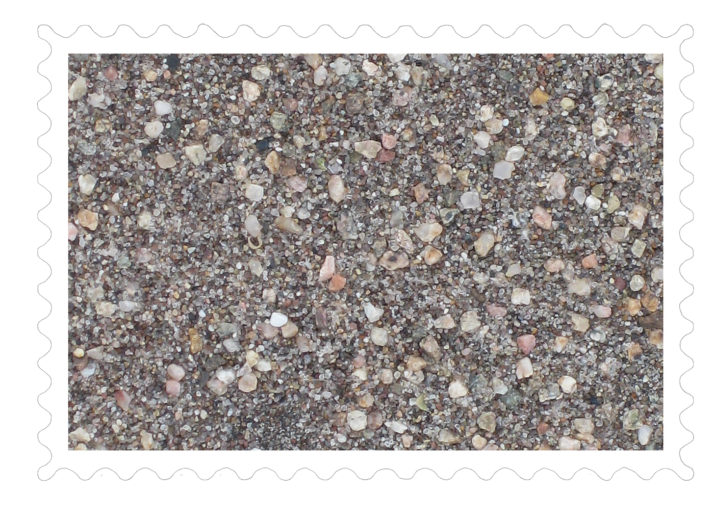 Close-up of sand at Great Sand Dunes National Park.  There are larger grains and smaller grains.  The larger grains are different colors: tan, pink, orange, white.  The smaller grains are mostly clear or black.