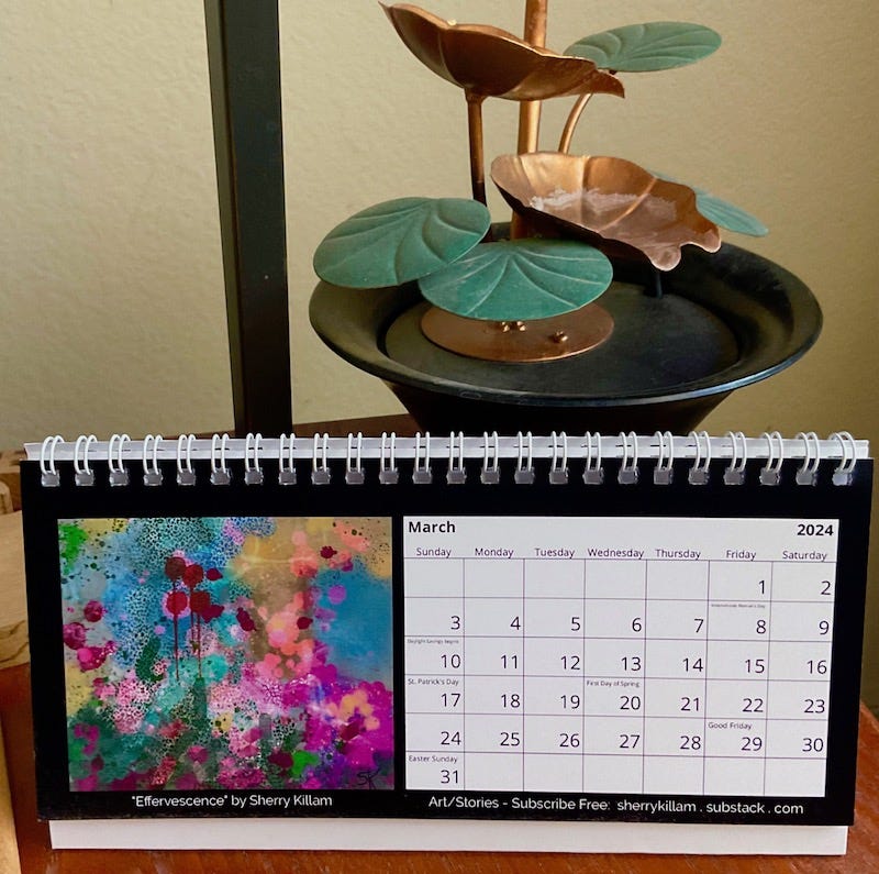 Desktop calendar with pink and magenta floral paired on a table with green metal water feature.