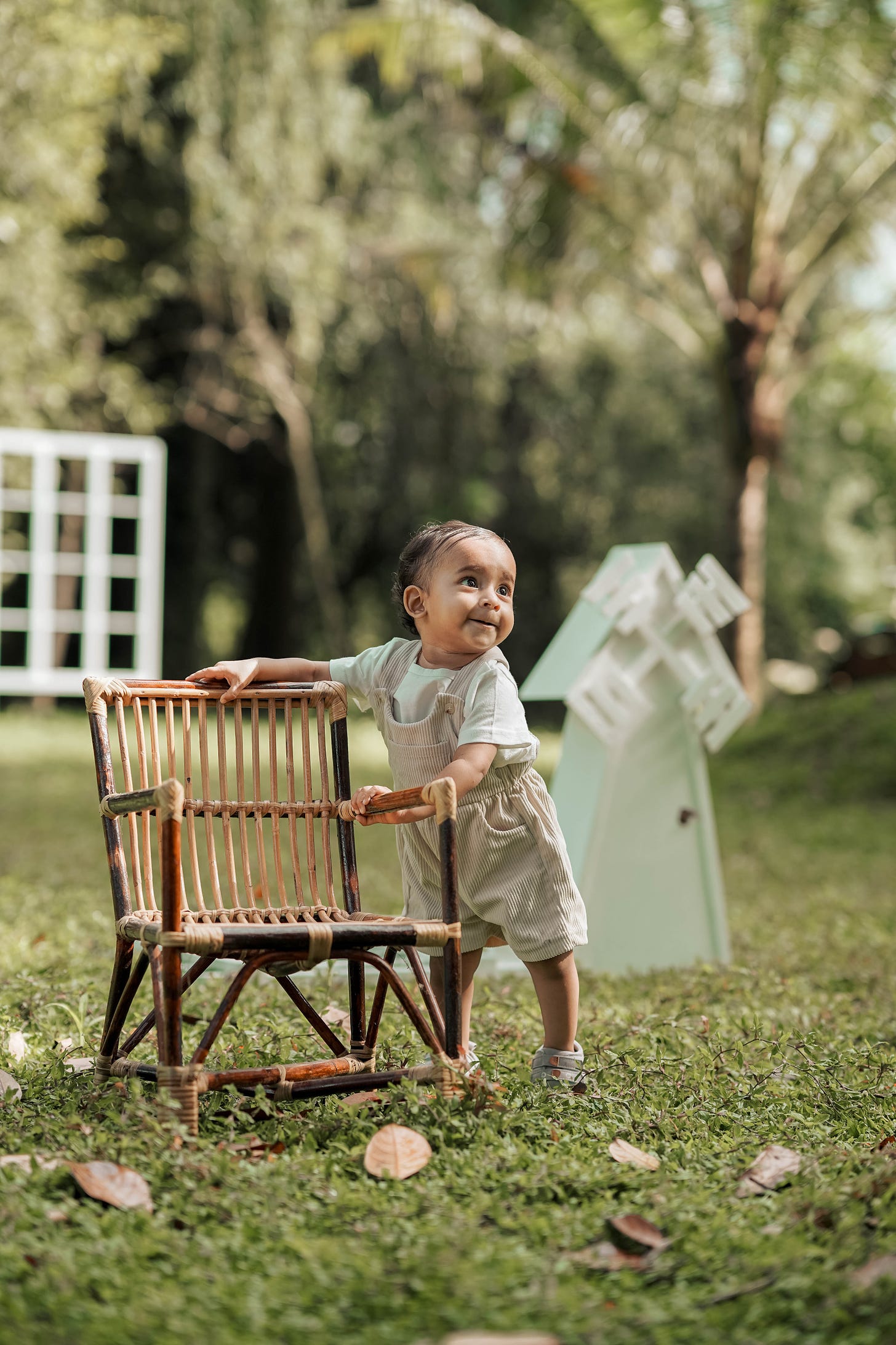 a toddler setting up a chair in a lawn and trying to stand up on it