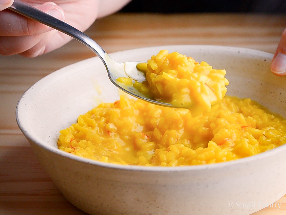 A spoonful of bright yellow risotto, flecked with saffron threads