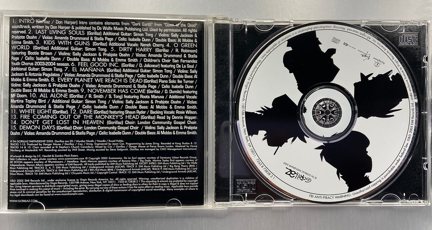 an open jewel case for Demon Days by Gorillaz, with the album booklet and disc visible.