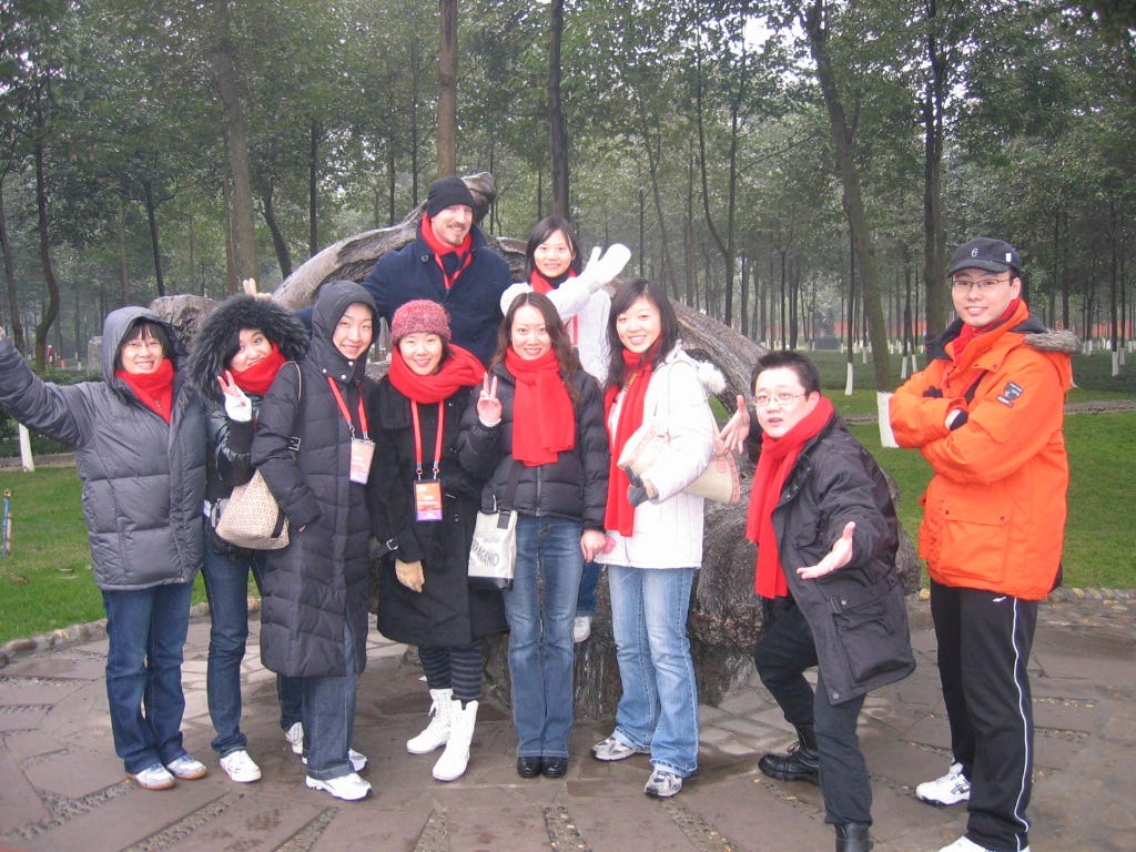 An American man stands with a group of nine Chinese colleagues all posing cheerfully for a snapshot and bundled up for cold weather.