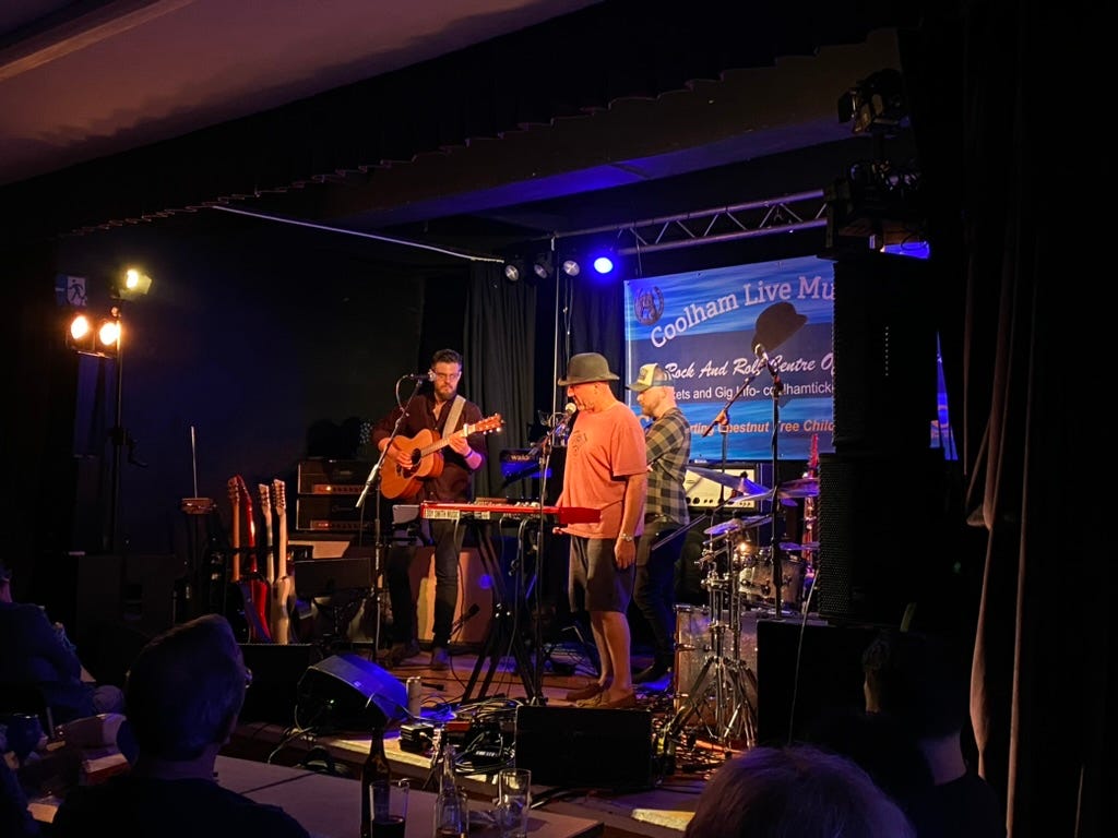 Man in hat on stage with two musicians