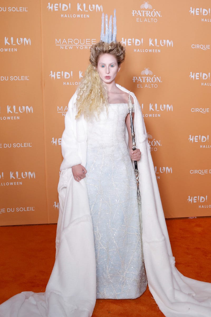 Alix Earle poses in her Jadis the White Witch costume, a floor-length white dress, white cape and silver staff.