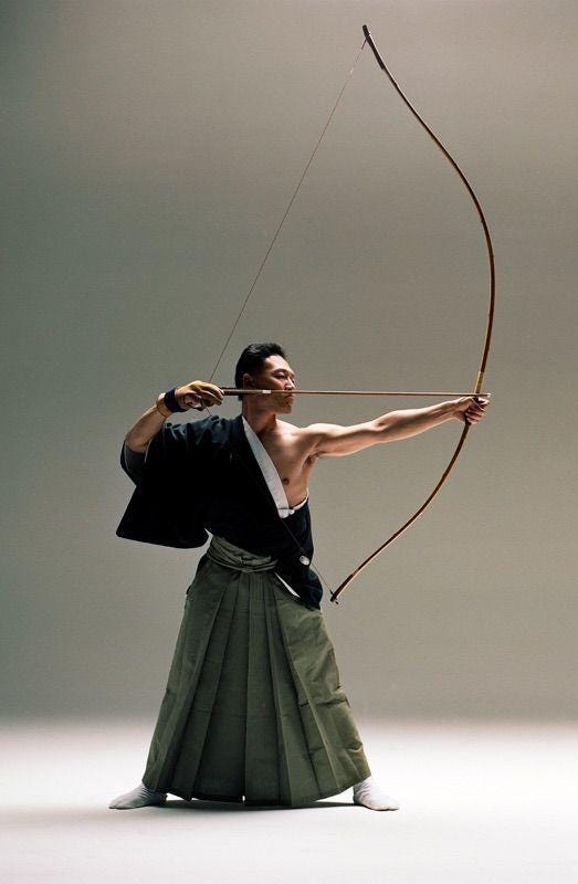 A person holding a bow and arrow

Description automatically generated