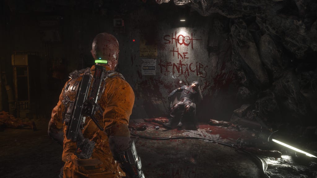 A screenshot of the protagonist of the Callisto protocol looking on a mural painted in blood on the wall which reads: SHOOT THE TENTACLES