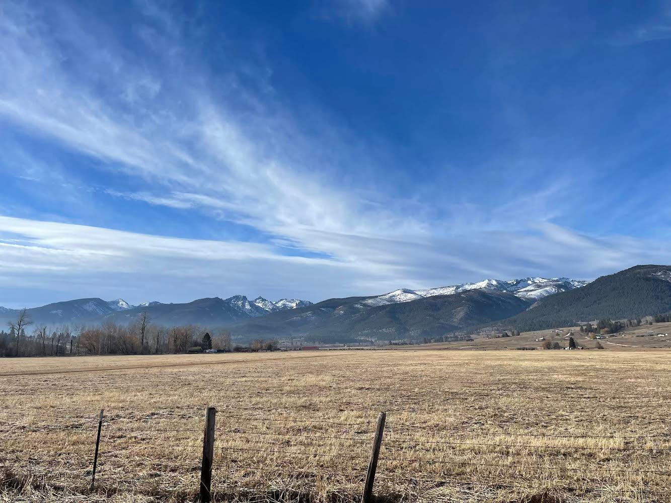 A photo of a trimmed field in front of a mountain range.