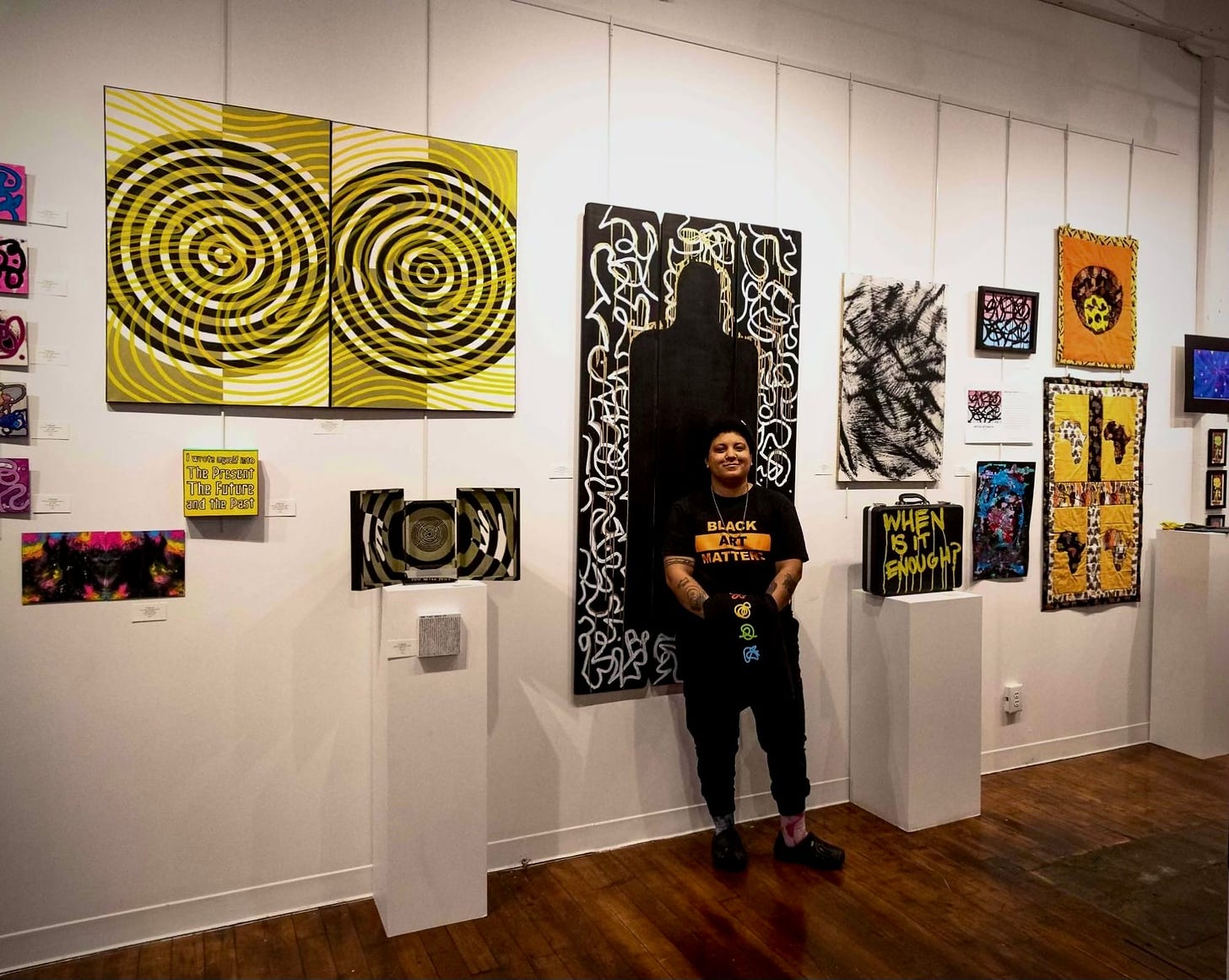 Blackfuturism Curator TJ Mundy standing in front of their work at the show.
