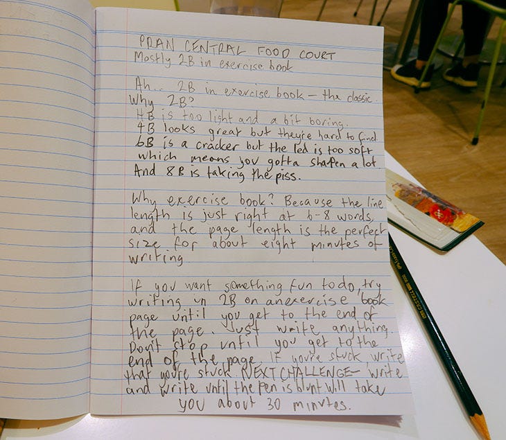 Pran Central Food Court, mostly to be in exercise book. 2b in exercise book, the classic y, 2b HB is too light and a bit boring. 4b, looks great, but they're hard to find. 6b, is a cracker, but the lead is too soft, which means you've got to sharpen a lot, and a B is taking the piss. Why exercise book? Because the line length is just right at six to eight words, and the page length is the perfect size for about eight minutes of writing. If you want something fun to do, try writing in 2b on an exercise book page until you get to the end of the page. Just write anything. Don't stop until you get to the end of the page. If you're struck stuck, write that you're stuck. Next challenge right and right until the pencil is blunt will take you about 30 minutes. New page. So, what am I doing in the food court suburban shopping center, food courts, good places to write, especially if you're a copywriter, no I'm not going to do that.