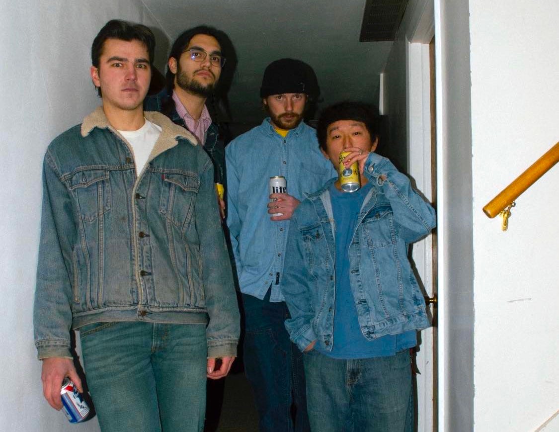 four dudes drinking beer in a hallway