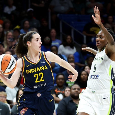 Indiana Fever guard Caitlin Clark (22) passes the ball as Dallas Wings forward Natasha Howard (6) defends during the first quarter of Friday's preseason game.