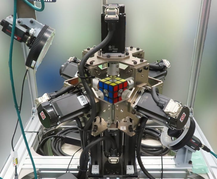 A mulit-armed servo robot, with a cube puzzle like a Rubik's Cube at its center.