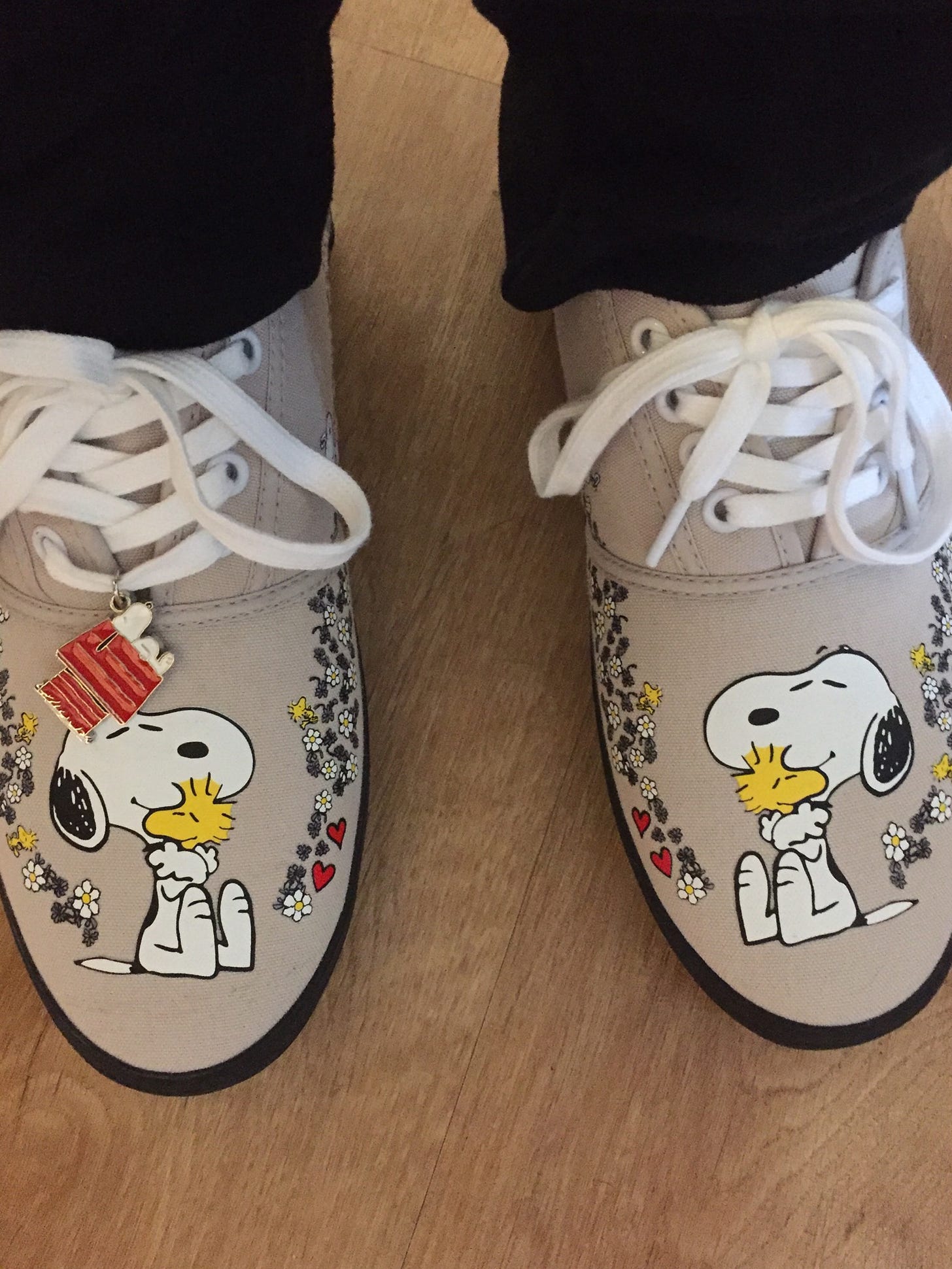 tan tennis shoes with a picture of Snoopy hugging Woodstock on them
