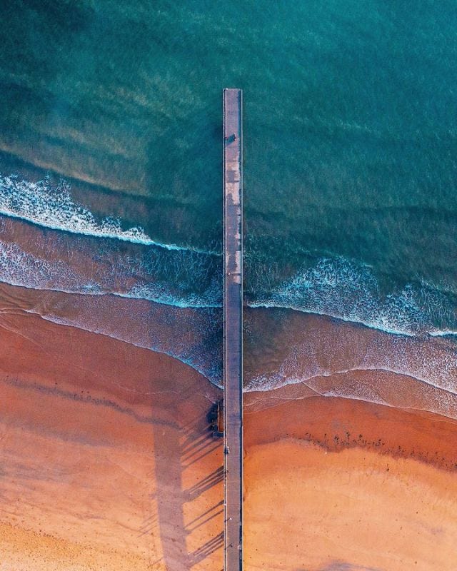 A long pier stretching out into the sea, viewed from above