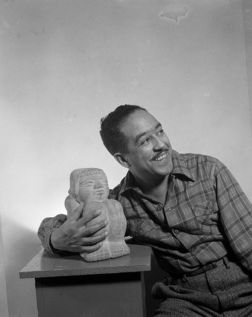 a black and white photograph of Langston Hughes side hugging a small statue and smiling