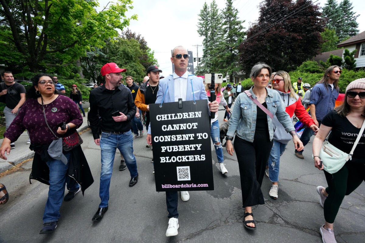 Chris Elston (C), also called "Billboard Chris," carries a billboard surrounded by supporters during a protest against gender ideology being taught in schools, in Ottawa on June 9, 2023. (The Canadian Press/Sean Kilpatrick)