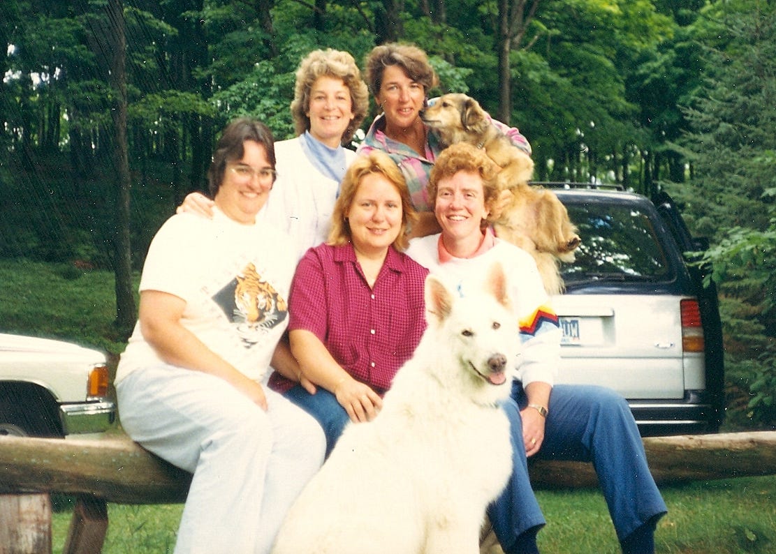 Five women and two dogs posing for a group photo