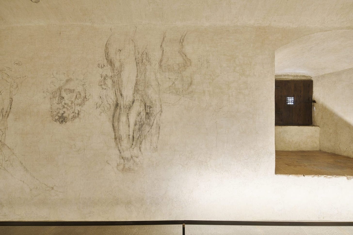 figurative charcoal drawings cover the beige walls of a room