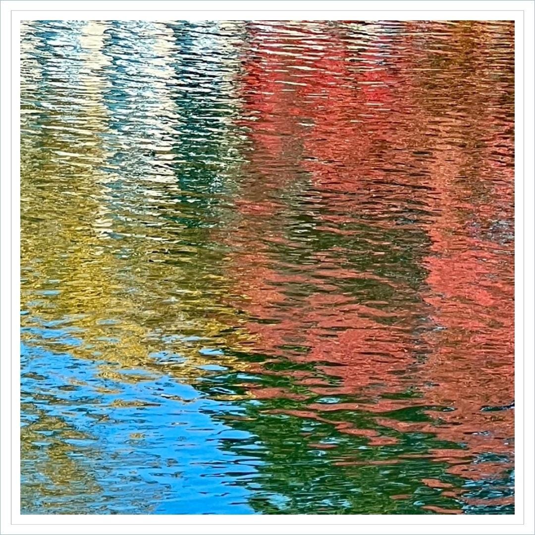 abstract image of reflection of red and yellow autumn leaves rippled across water