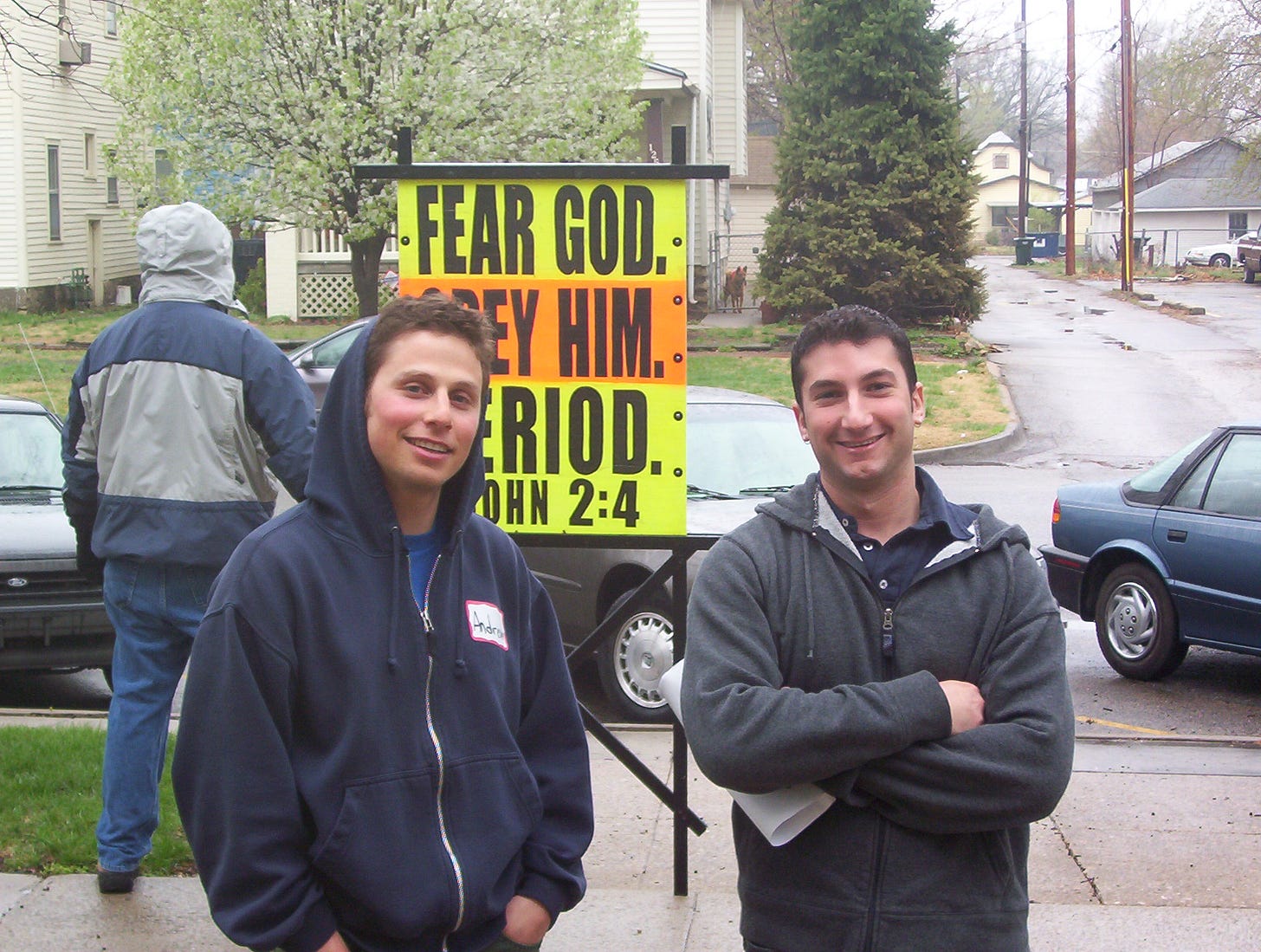 A group of men standing in front of a sign

Description automatically generated