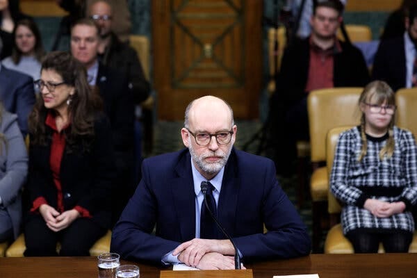 A truly evil-looking white guy with a grey beard in a suit as he testifies in Congress during his confirmation hearing.