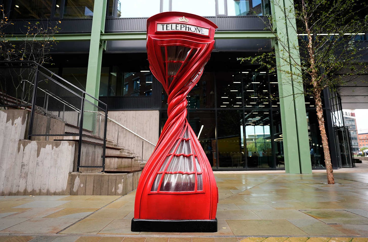 Sculpture that looks like a old-fashioned red British telephone booth, twisted in the middle like a tornado. 