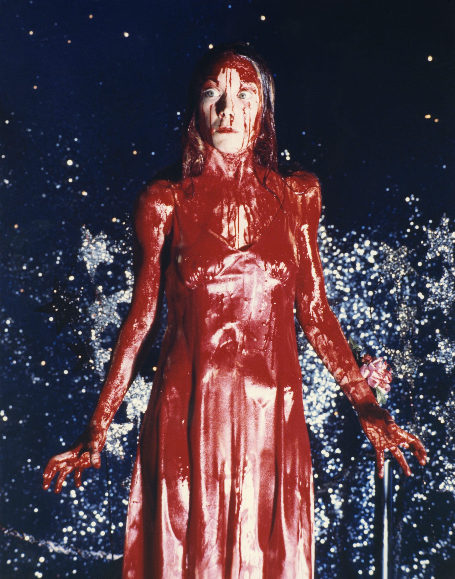 Carrie is soaked in blood on the prom stage, eyes wide open with rage and terror (Carrie, 1976) 