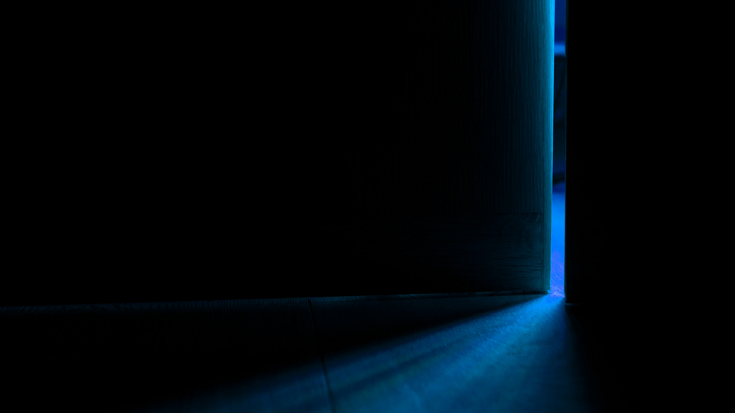A door opened slightly. Blue light leaks into the darkness.
