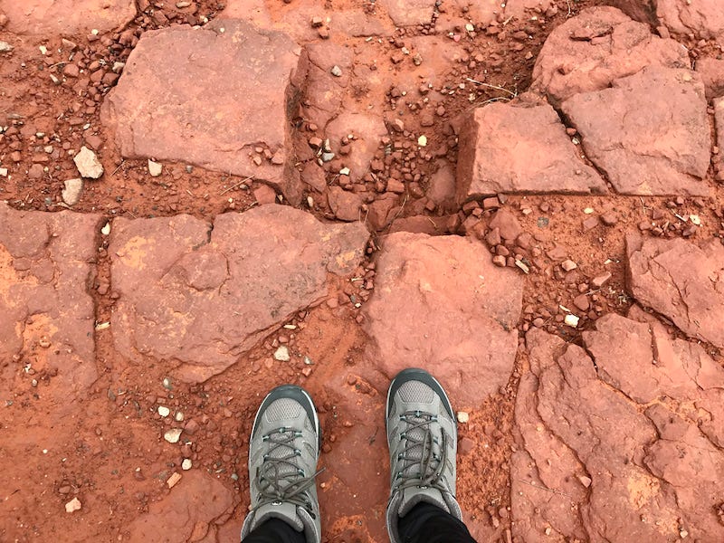 Photo of red-rock hiking trail with hiker's boots in the photo