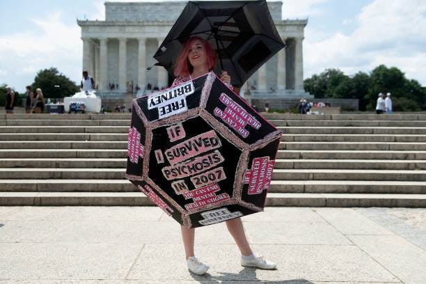 Melanie Carlson holds up umbrellas decorated with her message during a rally in front of the Lincoln Memorial protesting the conservatorship of...