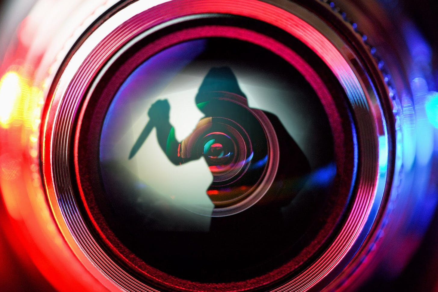 A stylized shot of a security camera lens, which contains a silhouette holding a knife menacingly.