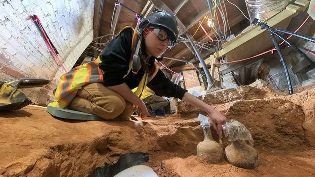 Archaeologist Tess Ostoyich carefully exposes two bottles in the mansion cellar at Mount Vernon. (Mount Vernon Ladies’ Association)