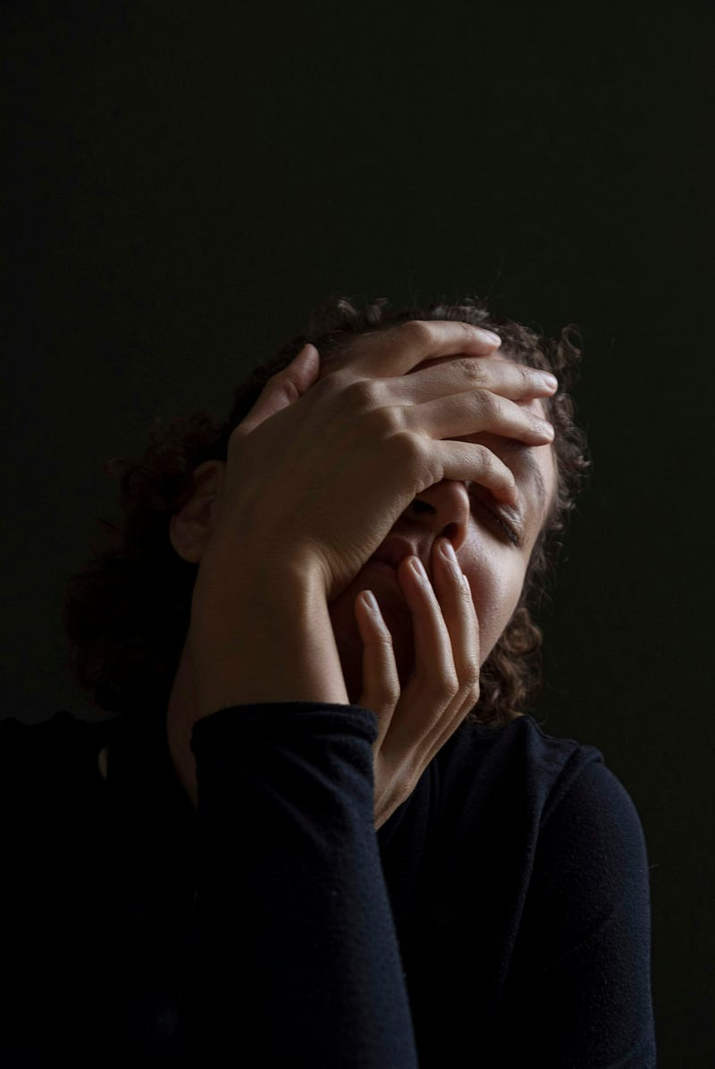 A woman covers her face with her hands.