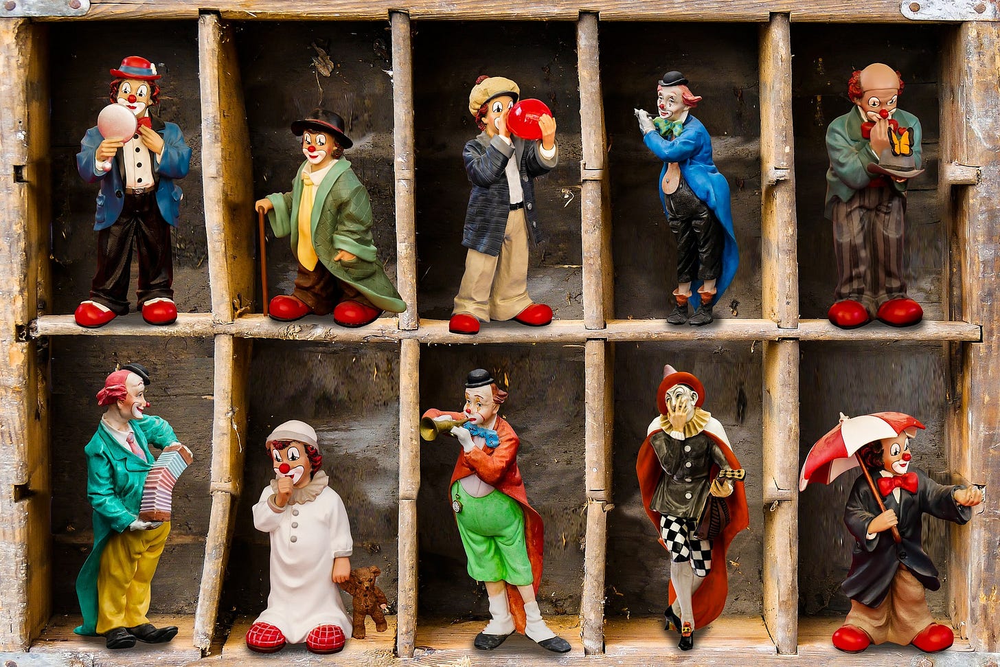 Two rows of five shelves each feature seven or eight-inch tall statues of clowns. Clowns each have distinct, colorful clothes ... blazers with large ties or no ties. Big baggy pants. All have oversised clothes, fact, and they're all doing steoretypical clown things. One's blowing a baloon. Another is plaing an accordion. Theey all have white face paint over their sadly lacking in diverse skin tones. Also, each has the big red nose. Two rows of five shelves each feature seven or eight-inch tall statues of clowns. Clowns each have distinct, colorful clothes ... blazers with large ties or no ties. Big baggy pants. All have oversised clothes, fact, and they're all doing steoretypical clown things. One's blowing a baloon. Another is plaing an accordion. Theey all have white face paint over their sadly lacking in diverse skin tones. Also, each has the big red nose.