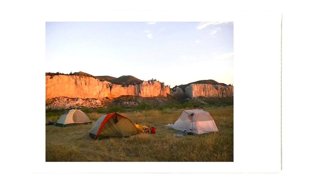 Tents with the mountains behind them lit up by the sunrise