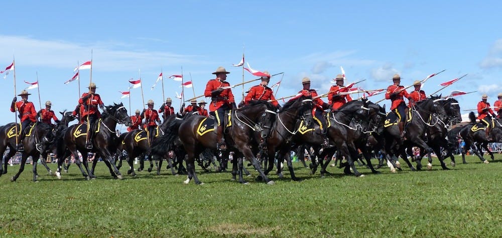 Free Canadian Mounties in red uniforms riding horses at an outdoor event. Stock Photo