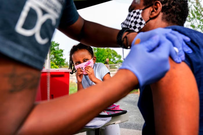 A child watches her father receive a Covid vaccination in Washington during the pandemic