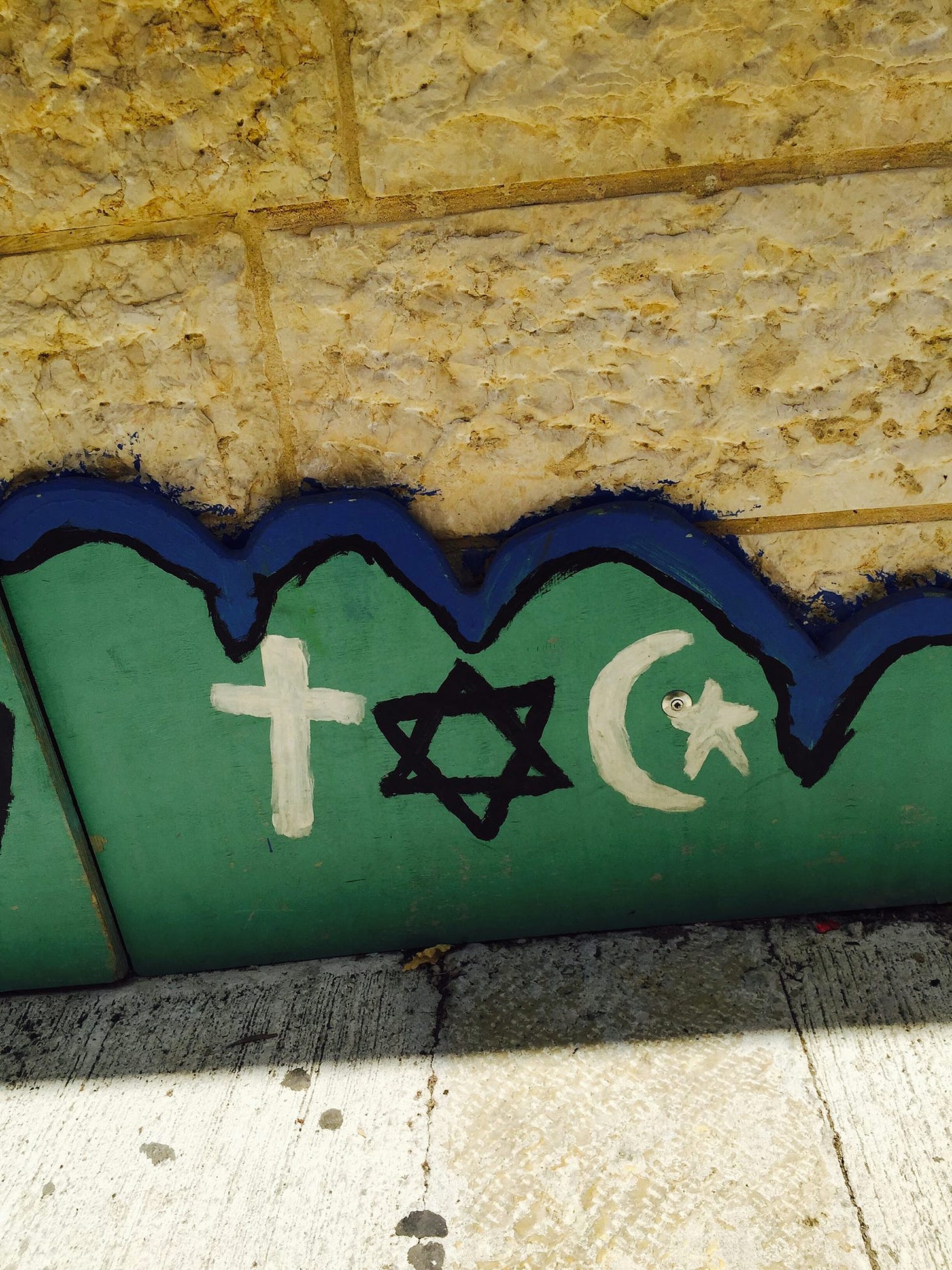 hand-painted detail of a cross, a star of David and a crescent with a star on a wooden side of the walkway