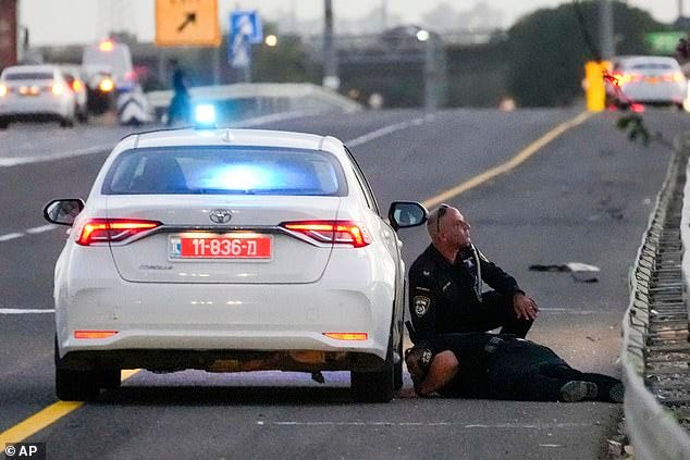 Police officers take cover as a siren sounds a warning of incoming rockets fired from Lebanon, in central Israel