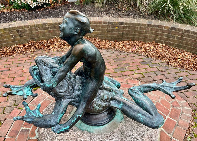 A statue of a child riding a frog

Description automatically generated