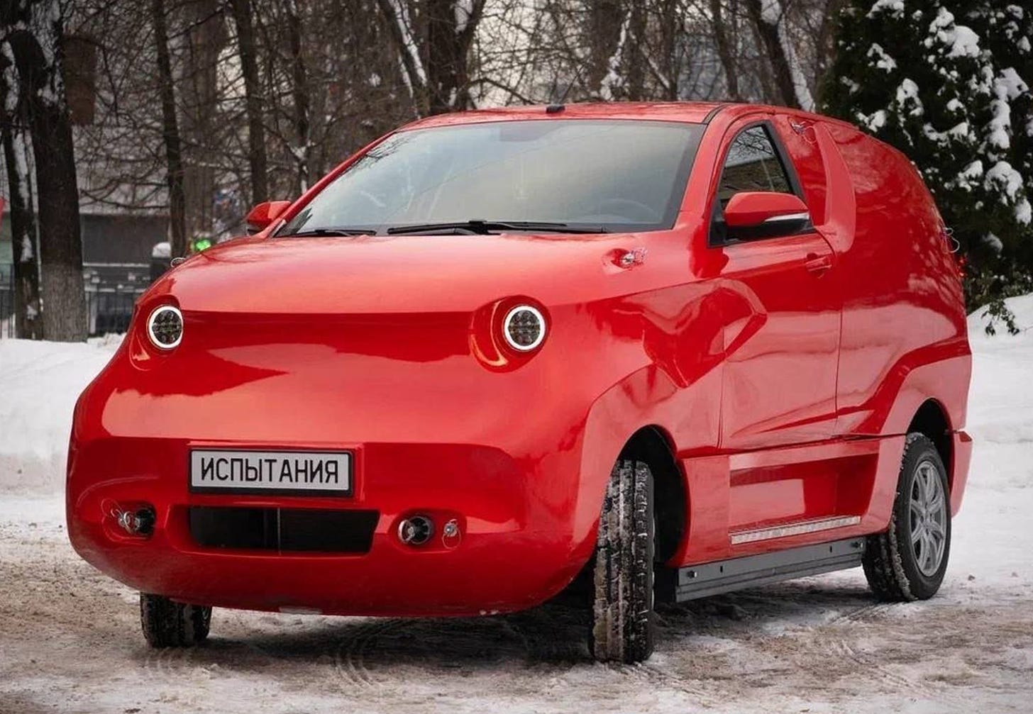 A strange, squat red car with headlights that look like terrified eyeballs