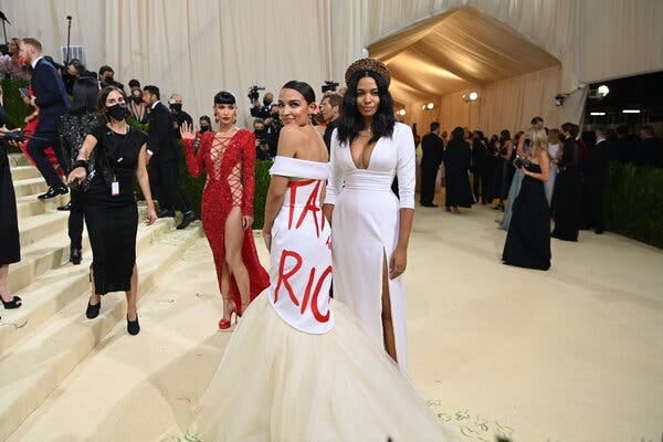 Alexandria Ocasio-Cortez and another woman show off their dresses at the Met Gala.