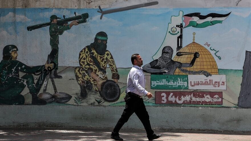 A Palestinian man walks next to graffiti depicting Hamas fighters firing rockets, in Khan Younis town in the southern Gaza Strip, on May 30, 2022. Photo by Abed Rahim Khatib/Flash90.