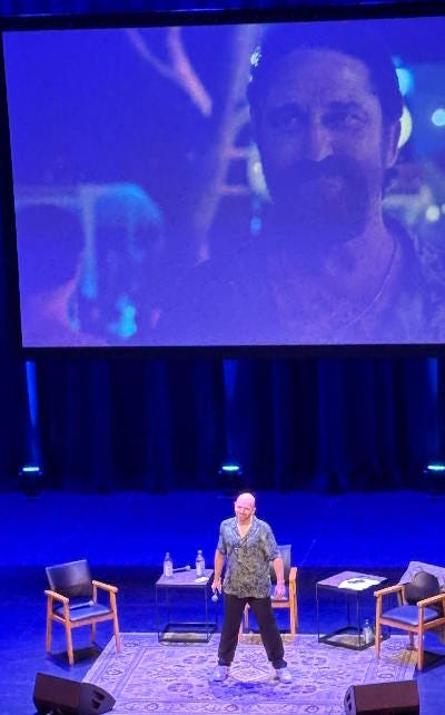 Paul Scheer in front of the screen showing Gerard Butler