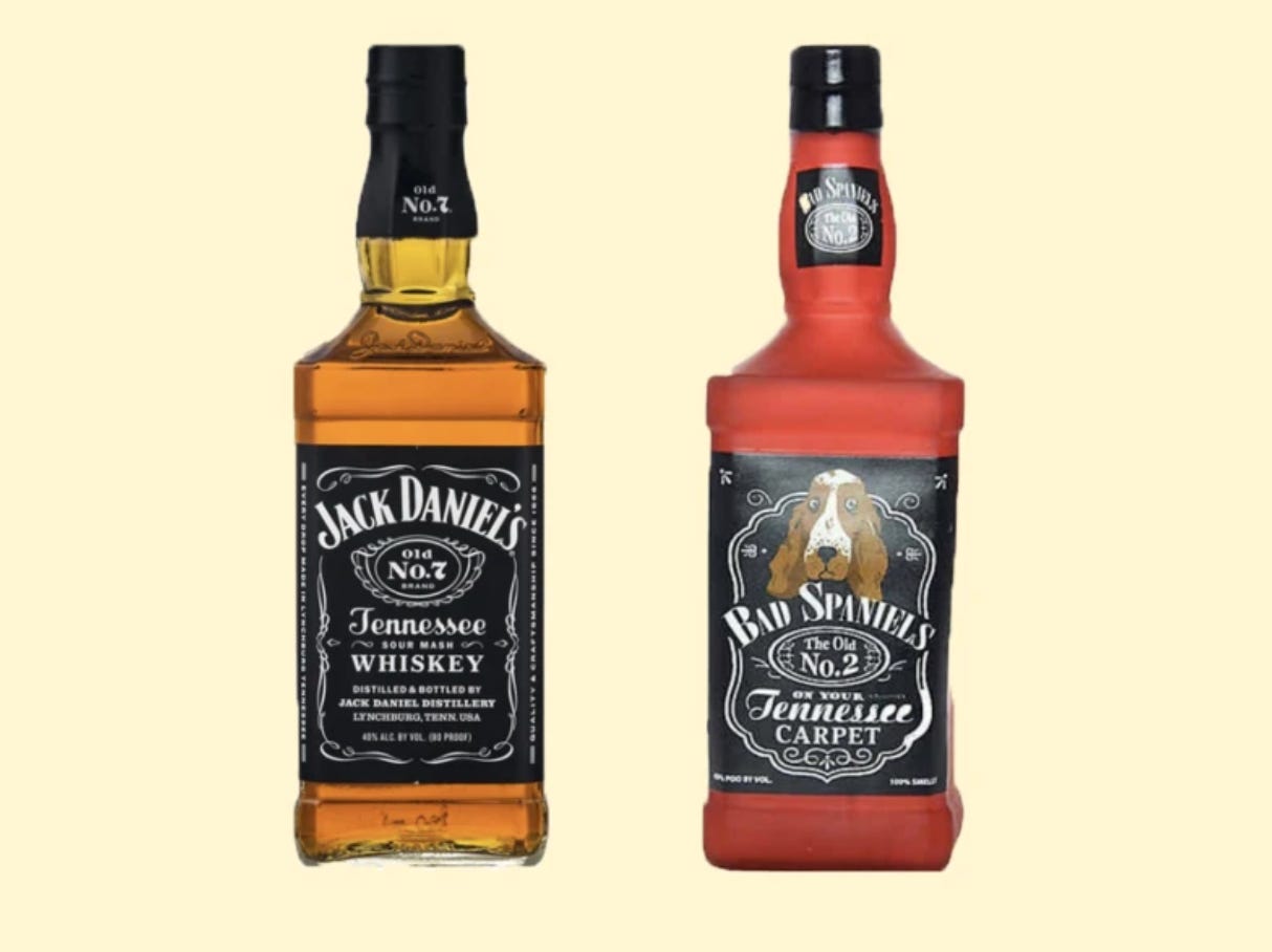Side by side comparison photo of a bottle of Jack Daniel’s Old No. 7 Tennessee Sour Mash Whiskey (left) and a dog toy that looks roughly the same shape with printing that reads “Bad Spaniel’s The Old No. 2 on your Tennessee Carpet” (right). 