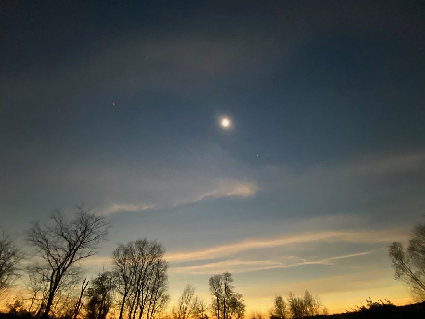 The total solar eclipse leaves a twilight in all directions, with planets (and a drone) visible in the darkened sky.
