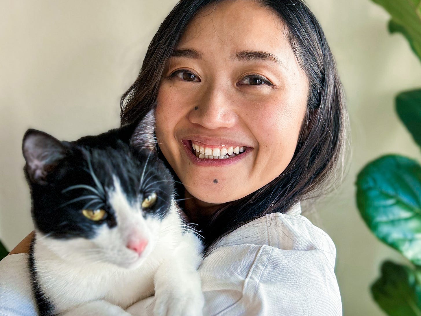 Woman with brown hair smiling and holding a cat