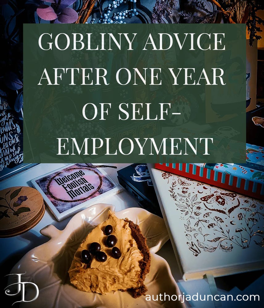 A photo of a desk with blue and purple plants, a present box stacked on a notebook with golden moths, a leaf plate with peanut butter pie, coasters with belladonna and one that says "Welcome, foolish mortals." Over the image is the text "Gobliny Advice After One Year of Self-Employment"