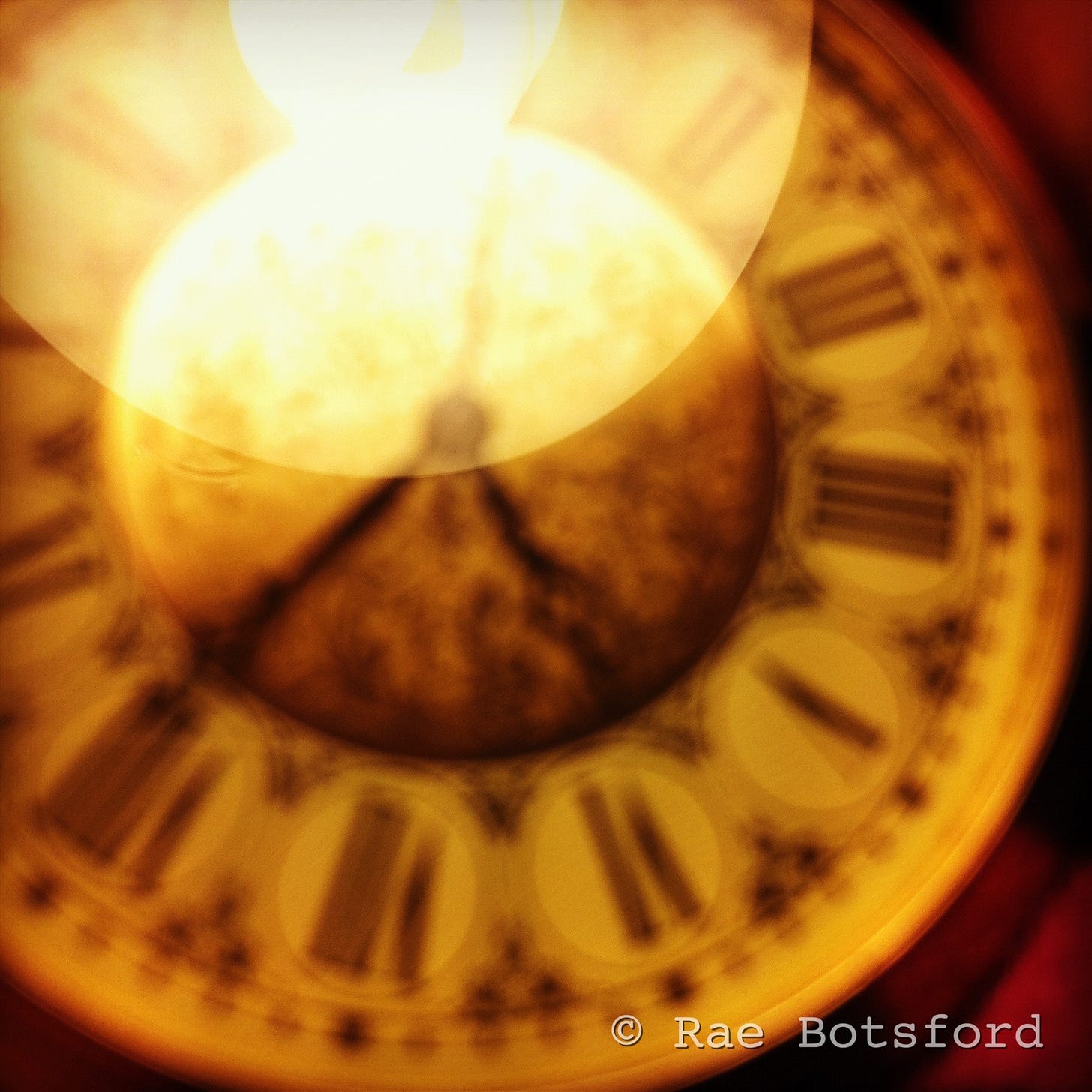 blurry image of clock with Roman numerals, watermarked Rae Botsford