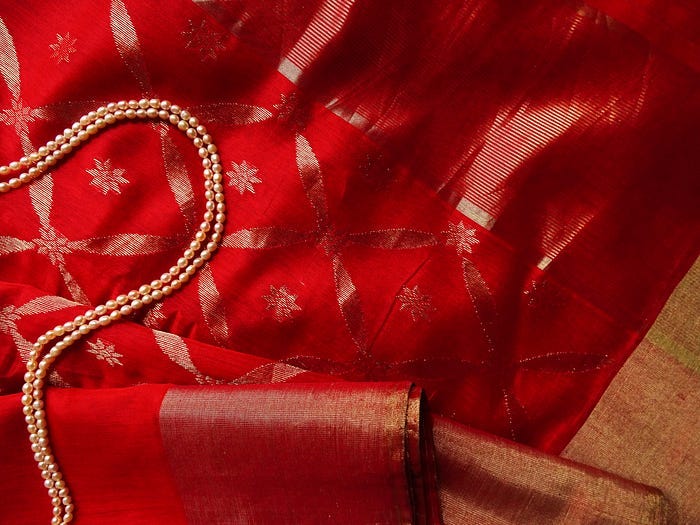 a string of pearls against a red silk sari